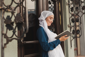 Portrait of young muslim woman wearing hijab reading book outdoor