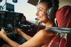 Young cute woman holding the helm while sitting in the cockpit